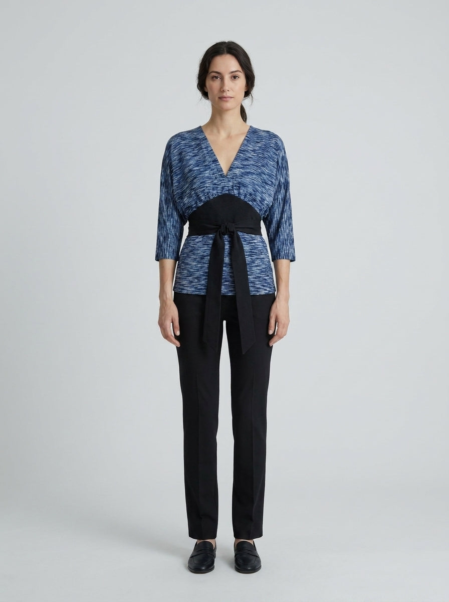 Dama con blusa azul jaspeada tipo kimono y faja negra anudada para anfitriona de restaurante asiático.