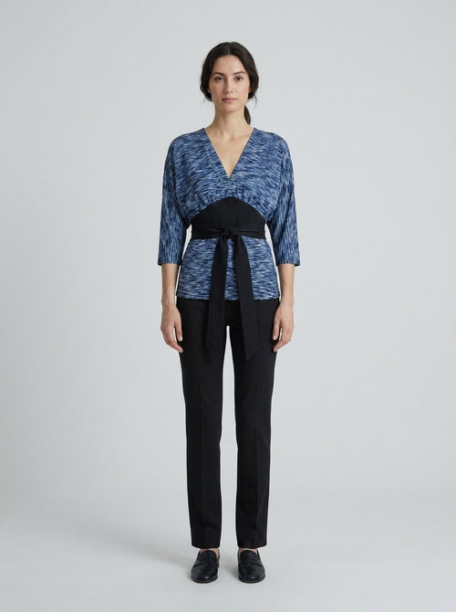 Dama con blusa azul jaspeada tipo kimono y faja negra anudada para anfitriona de restaurante asiático.