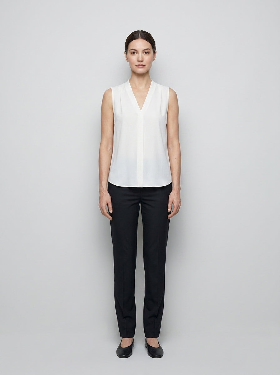 Uniforme para recepcionista de hotel con blusa blanca sin mangas cuello en V y plisé frontal, fabricada por Qualtus.