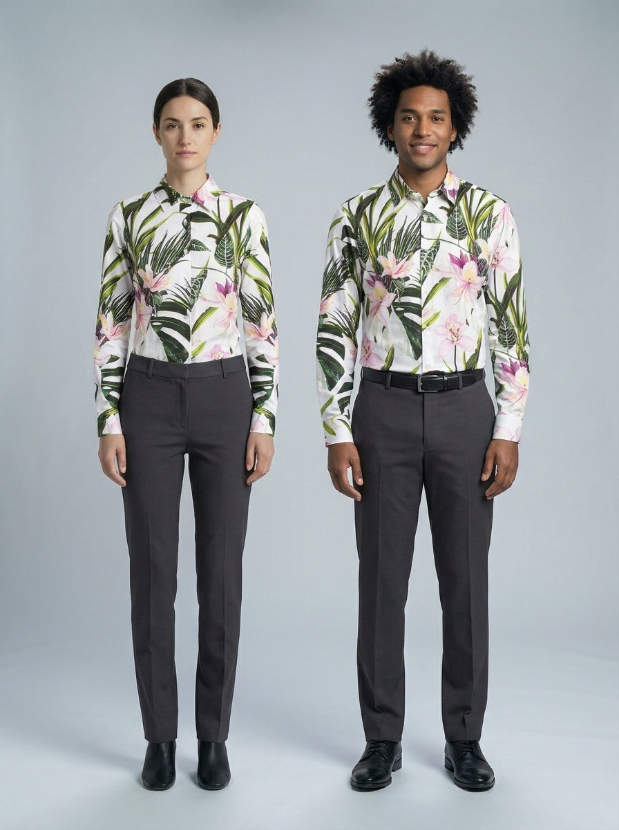 Dama y caballero con blusa y camisa de estampado floral tropical rosa y verde, pantalón gris, para resort.