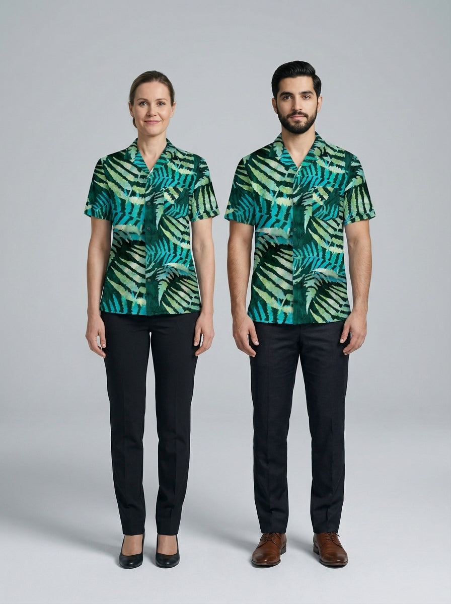 Dama y caballero con blusa y camisa de estampado de helechos verde y pantalón negro, para resort.