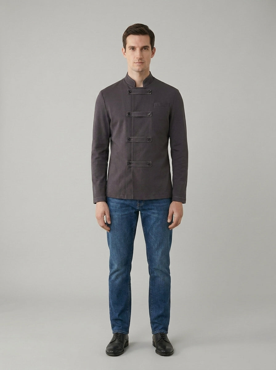 Caballero con chaqueta gris de cuello mao y cierre de presillas estilo asiático sobre jeans para restaurante.