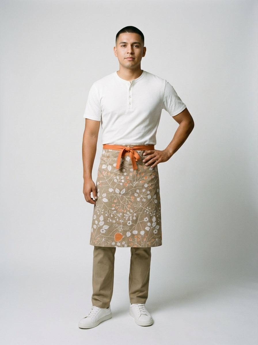 Mandil medio en tela con estampado botánico beige y naranja combinado con camiseta blanca lisa.