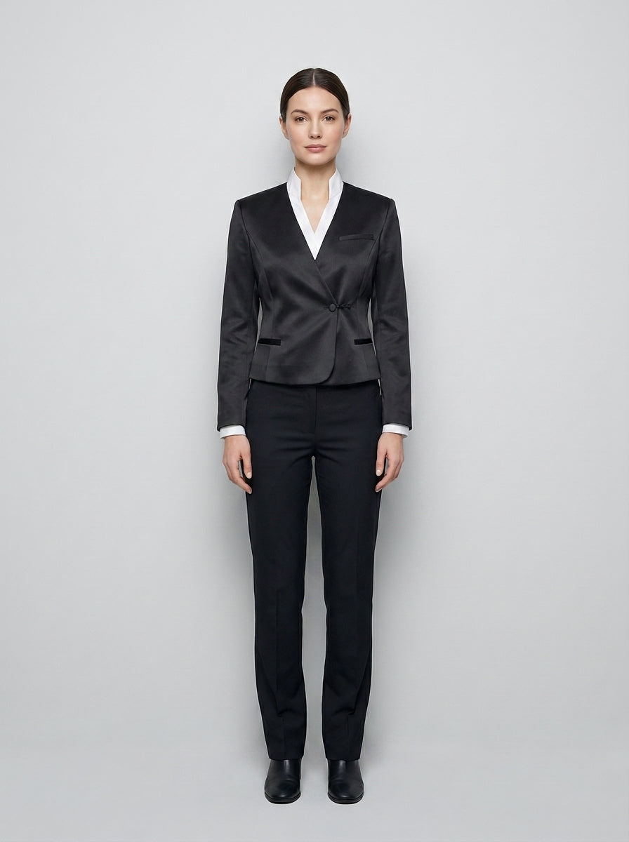 Dama con saco gris satinado de cuello cruzado sobre camisa blanca y pantalón negro para anfitriona de restaurante.