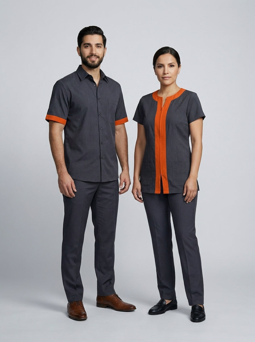 Caballero con camisa gris de ribete naranja y dama con blusa gris de cierre y franja naranja para camarista y mozo de hotel.