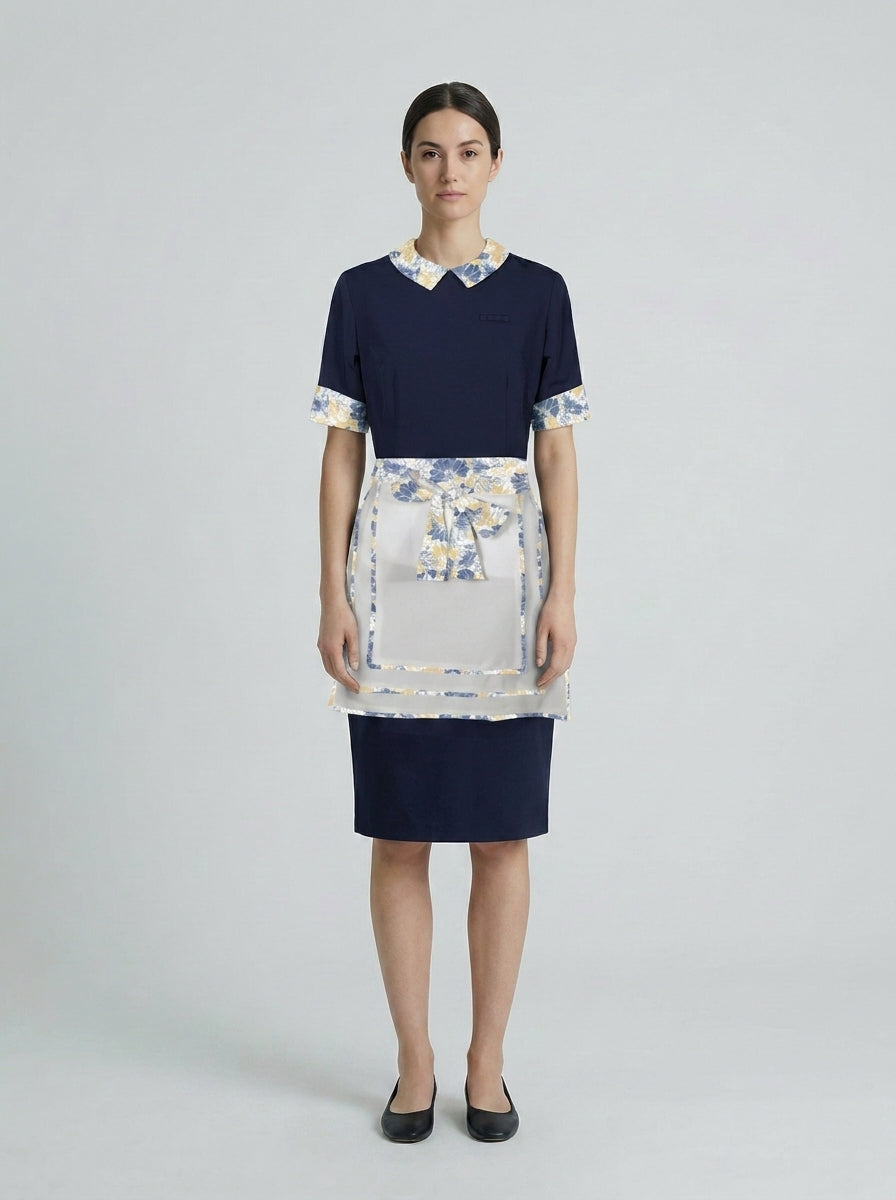 Dama con vestido azul marino de cuello floral azul y amarillo con mandil floral y falda para camarista de hotel.